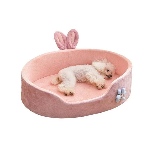 Pink detachable pet bed with rabbit ears and flower decoration, soft velvet fabric, and a small white dog sleeping inside.